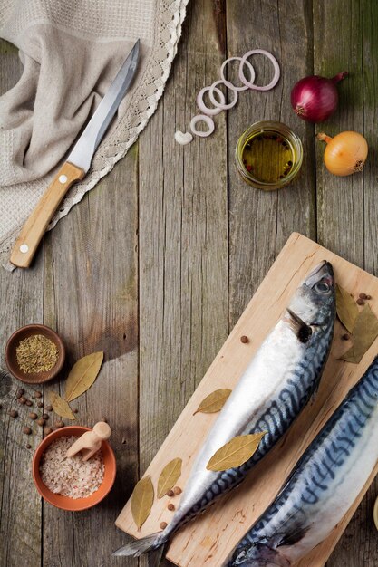 Roher Makrelenfisch mit Zutaten zum Kochen auf einem hölzernen alten Hintergrund Selektiver Fokus Rustikaler Stil Draufsicht