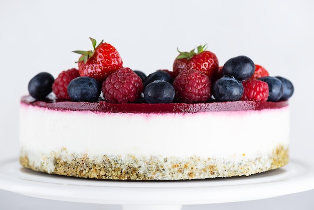 Roher Mousse-Kuchen mit Beeren auf hellem Hintergrund. Zucker, Gluten, laktosefrei, vegan.