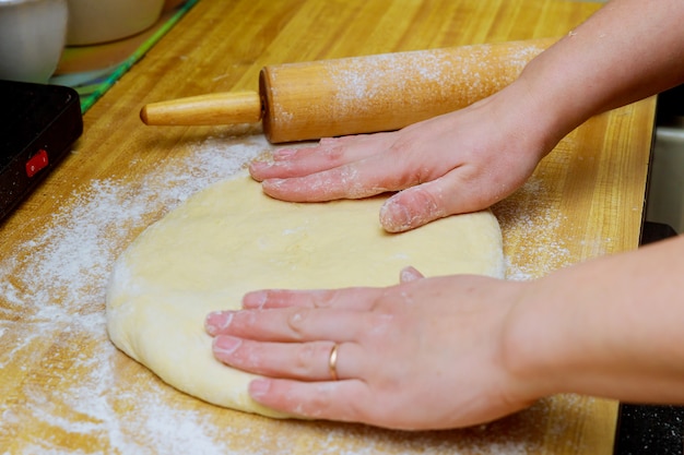 Roher Pizzateig mit Bestandteilen auf Holztisch