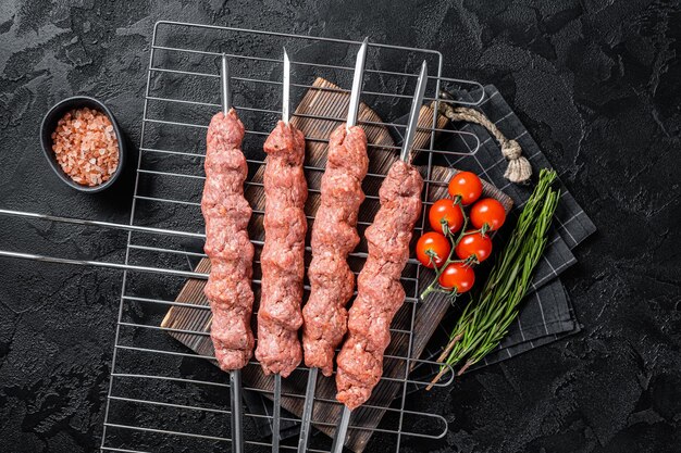 Roher Schaschlik aus Lammhackfleisch und Rindfleisch Türkischer Adana-Kebab auf Spießen Schwarzer Hintergrund Ansicht von oben