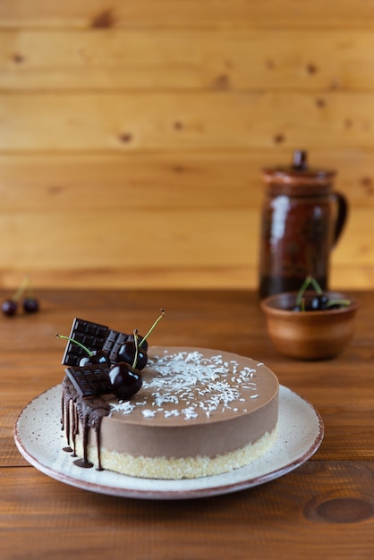 Foto roher schokoladenmousse-kuchen mit kirschen auf einem holztisch