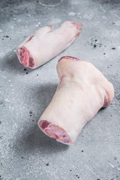 Roher Schweinehuf, Füße, Traber auf einem Metzgerbrett. Grauer Hintergrund. Ansicht von oben.