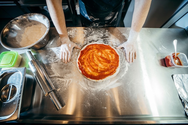 Roher teig für die pizzazubereitung mit zutat: tomatensauce, mozzarella, tomaten,