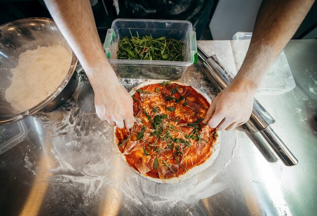 Roher Teig für die Pizzazubereitung mit Zutaten: Tomatensauce, Mozzarella, Käse, Schinken