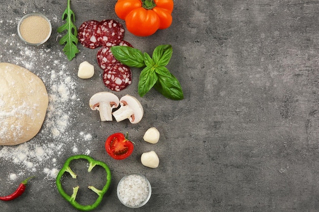 Foto roher teig für pizza mit zutaten und gewürzen auf dem tisch