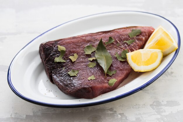 Roher Thunfisch mit Zitrone und Lorbeerblatt auf Keramik