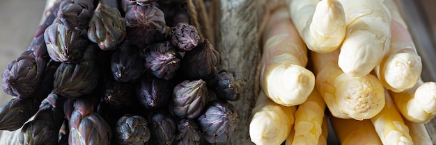 Roher, weiß-violetter Spargel im Korb auf Holzhintergrund. Gesundes Ernährungskonzept