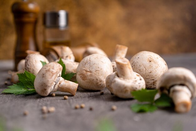 Foto roher weißer pilz, champignons und pfeffer auf grauem hintergrund zum kochen von frischen zutaten