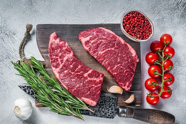 Rohes Denver geschnittenes schwarzes Angus-Bio-Steak auf einem Metzger-Schneidebrett mit Kräutern