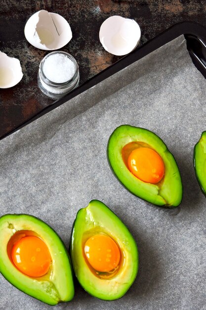 Rohes Ei in der Avocado auf einem Backblech. Avocado mit Ei kochen. Keto-Mittagsrezept.