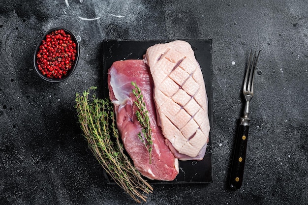 Rohes Entenbrustfilet Geflügelfleischsteaks mit Kräutern Schwarzer Hintergrund Ansicht von oben