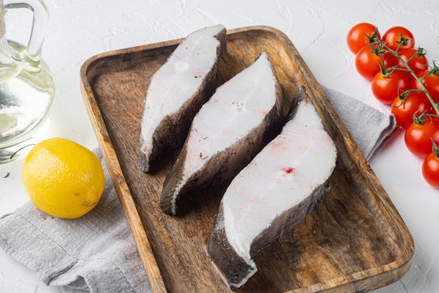 Rohes Fischsteakset, mit Zutaten und Rosmarinkräutern, auf weißem Steintischhintergrund