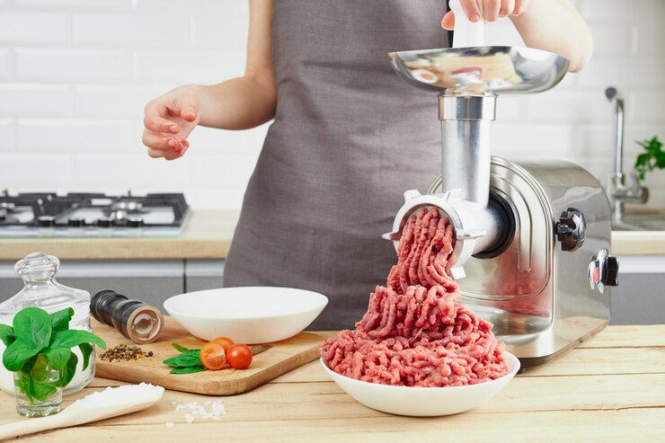 Rohes Fleisch. Der Prozess der Zubereitung von Hackfleisch mittels eines Fleischwolfs. Weibliche Hände benutzen Fleischhacker in der Küche.