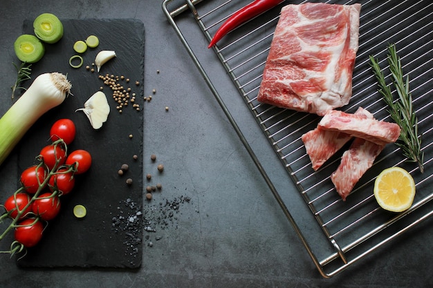 Rohes Fleisch Frisches rohes Schweinefleisch Rippen mit Zutaten und Gewürzen auf schwarzem Hintergrund Menükonzept Top-View Kopierraum