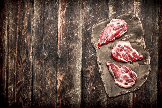 Rohes Fleisch Hintergrund. Fleischstücke auf dem alten Brett. Auf hölzernem Hintergrund.