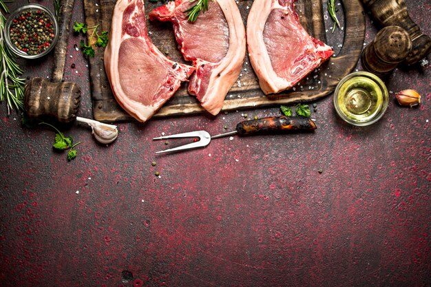 Rohes Fleisch Hintergrund. Rohe Schweinefleischstücke auf Knochen auf rustikalem Metalltisch.