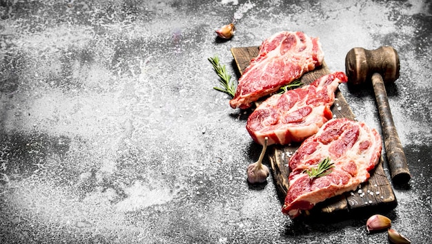 rohes Fleisch Hintergrund. Rohes Schweinefleisch mit Gewürzen und Kräutern. auf einem rustikalen Tisch.