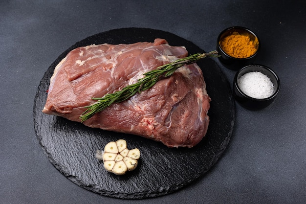 rohes Fleisch mit Gewürzen auf dunklem Hintergrund