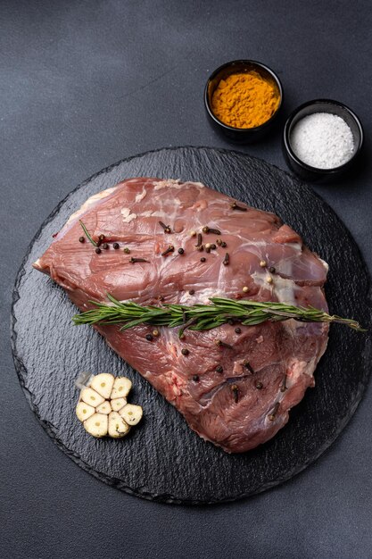 rohes Fleisch mit Gewürzen auf dunklem Hintergrund