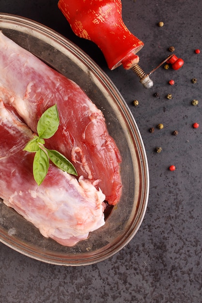 Rohes Fleisch mit Gewürzen auf einem schwarzen Hintergrund