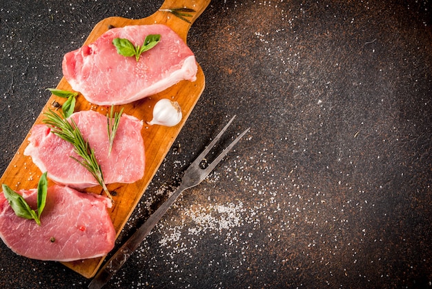 Rohes Fleisch, Schweinesteaks mit Gewürzen, Kräutern, Olivenöl