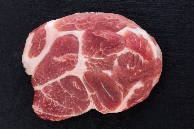 Rohes Fleisch, Steak auf schwarzem Hintergrund, Ansicht von oben.