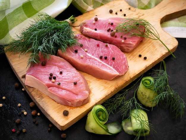 Foto rohes fleischsteak auf einem holzbrett gewürze dillpaprika und gurkenrolle bereit zum kochen