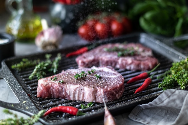 Rohes frisches Fleisch. Steak für zwei mit Zutaten in einer Grillpfanne, mit Gewürzen, Gemüse und Kräutern