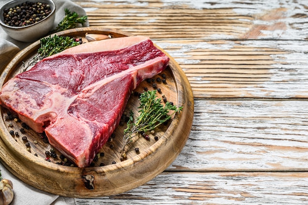 Rohes frisches Fleisch-T-Bone-Steak mit Gewürzen, Knoblauch und Rosmarin. Bio-Rindfleisch mit Knochen. Draufsicht. Speicherplatz kopieren