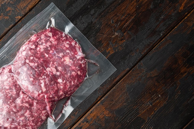 Rohes frisches Rindfleisch Burger Hackfleisch in Plastikschale auf alten dunklen Holztisch Hintergrund Draufsicht flach lag mit Kopie Platz für Text