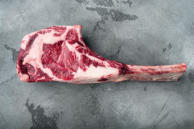 Rohes frisches Tomahawk Black Angus Prime Beef Chop Steak auf grauem Steinhintergrund Draufsicht flach lag mit Kopierraum für Text