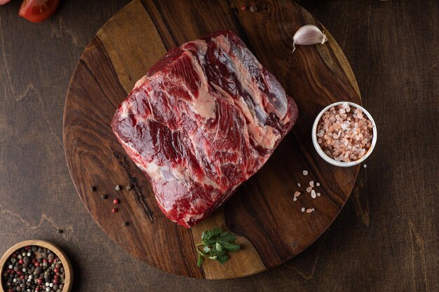 Rohes Frischfleisch-Ribeye-Steakgewürz und frische Tomate auf Holzhintergrund