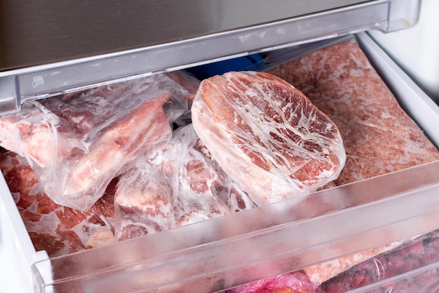 Rohes gefrorenes Fleisch. Rohe Schweinekoteletts im Gefrierschrank. Gefrorenes Essen