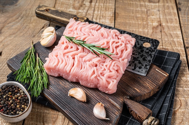 Rohes gehacktes Hühner- und Truthahnfleisch auf Schneidebrett aus Holz mit Metzgererbeil. hölzerner Hintergrund. Ansicht von oben.