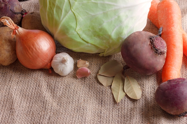 Rohes Gemüse für Rübensuppe Borschtsch. Weißkohl, rote Rübe, Karotte, Kartoffel, Tomate, Knoblauch auf einem hölzernen Brett