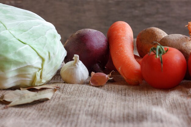 Rohes Gemüse für Rübensuppe Borschtsch. Weißkohl, rote Rübe, Karotte, Kartoffel, Tomate, Knoblauch auf einem hölzernen Brett