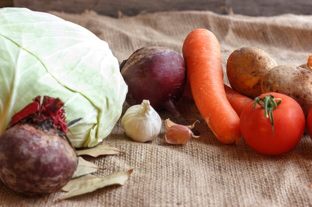 Rohes Gemüse für Rübensuppe Borschtsch. Weißkohl, rote Rübe, Karotte, Kartoffel, Tomate, Knoblauch auf einem hölzernen Brett