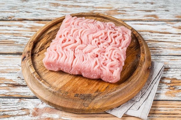 Rohes Hackfleisch oder gemahlenes Hühnerfleisch auf Holzbrett. Weißer Hintergrund. Draufsicht.