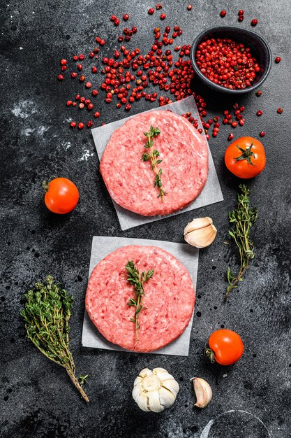 Rohes Hackfleischschnitzel, Rinderhackfleisch und Schweinefleisch. Burger Pastetchen auf Schwarz. Draufsicht