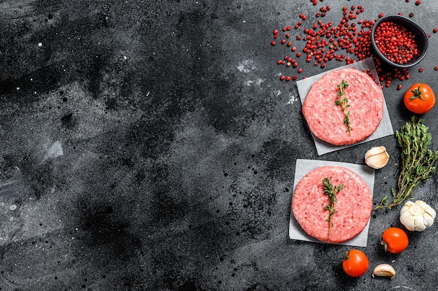 Rohes Hackfleischschnitzel, Rinderhackfleisch und Schweinefleisch. Burger Pastetchen. Schwarzer Hintergrund. Draufsicht. Speicherplatz kopieren.