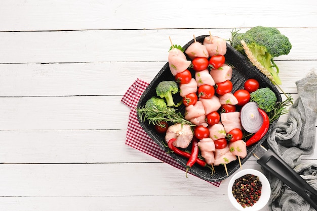 Rohes Hähnchen-Schaschlik mit Kirschtomaten Grill auf weißem Holzhintergrund Draufsicht Freier Kopierraum