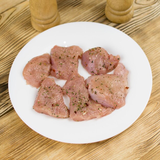 Rohes Hähnchenfilet mit Gewürzen auf Holzgrund bestreut Vorbereitung zum Kochen