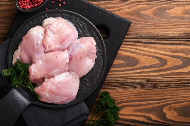 Rohes Hähnchenschenkelfilet ohne Haut mit Kräutern und Gewürzen auf altem Holzhintergrund Farm Geflügelfleisch Draufsicht mit Kopierbereich Mock up