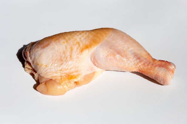 Rohes Hühnerbein in weißer Platte auf weißem Hintergrund