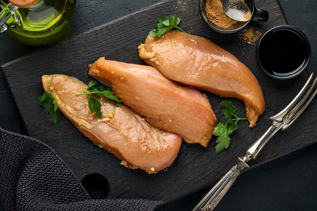 Rohes Hühnerfleischfilet mariniert in Teriyaki-Sojasauce, Zwiebeln, Knoblauch und Pfeffer in schwarzem Teller