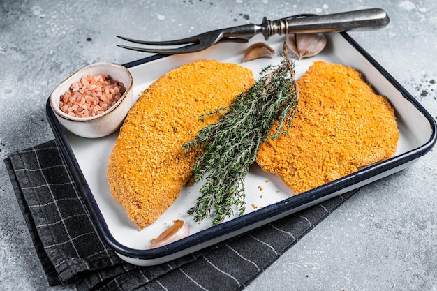 Rohes Hühnerschnitzel in Semmelbröseln kochen Ungekochtes Fleischsteak Grauer Hintergrund Ansicht von oben