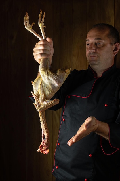 Rohes Huhn in der Hand des Kochens Hahnpräsentation vor der Zubereitung eines köstlichen Gerichtes in der Restaurantküche Auswahl einer Henne vor dem Braten oder Kochen