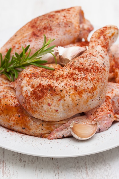 Rohes Huhn mit Pfeffer und Knoblauch auf weißem Teller