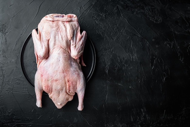 Rohes junges Gänsefleisch auf schwarzem Tisch, flach liegend, mit Kopienraum.