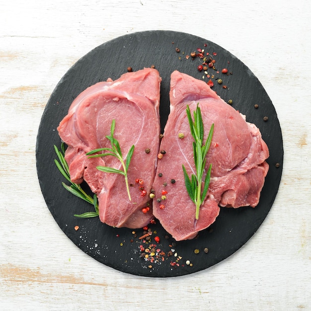 Rohes Kalbsfleisch Zwei rohe Steaks mit Gewürzen Draufsicht Freier Platz für Ihren Text